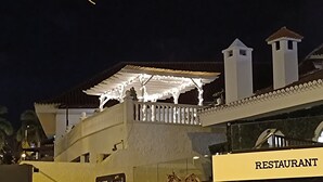 Un edificio con letrero de restaurante, un porche cubierto y dos chimeneas.