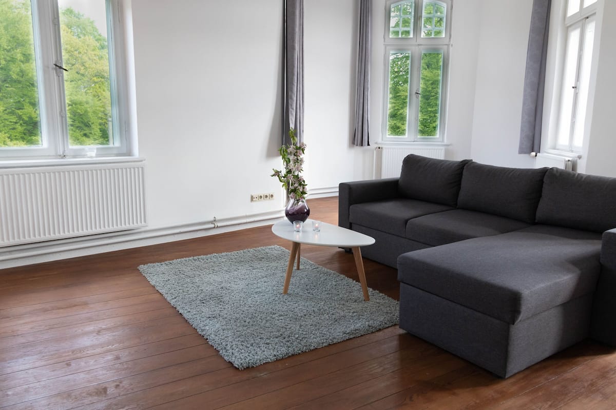 Una sala de estar moderna con un sofá gris, una mesa de centro blanca y una alfombra gris.