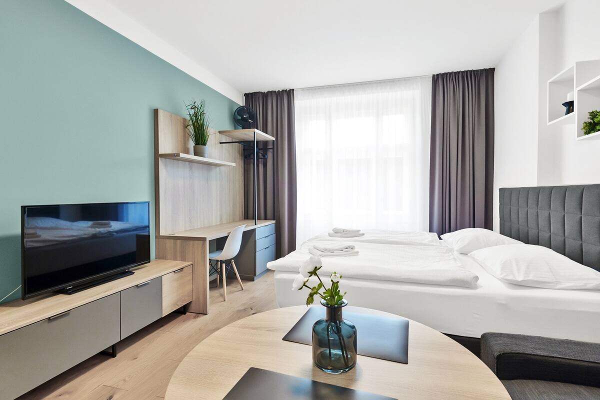 Una habitación de hotel moderna con televisión de pantalla plana, un escritorio, una cama cómoda y una pequeña zona de estar.