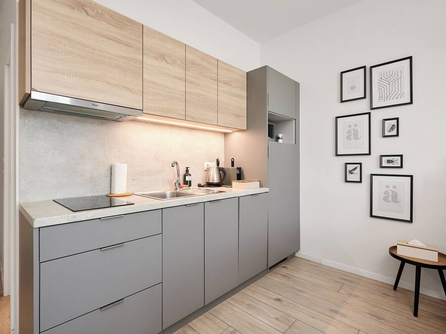 Una cocina moderna con gabinetes grises, un horno empotrado y una encimera con hervidor y cafetera.