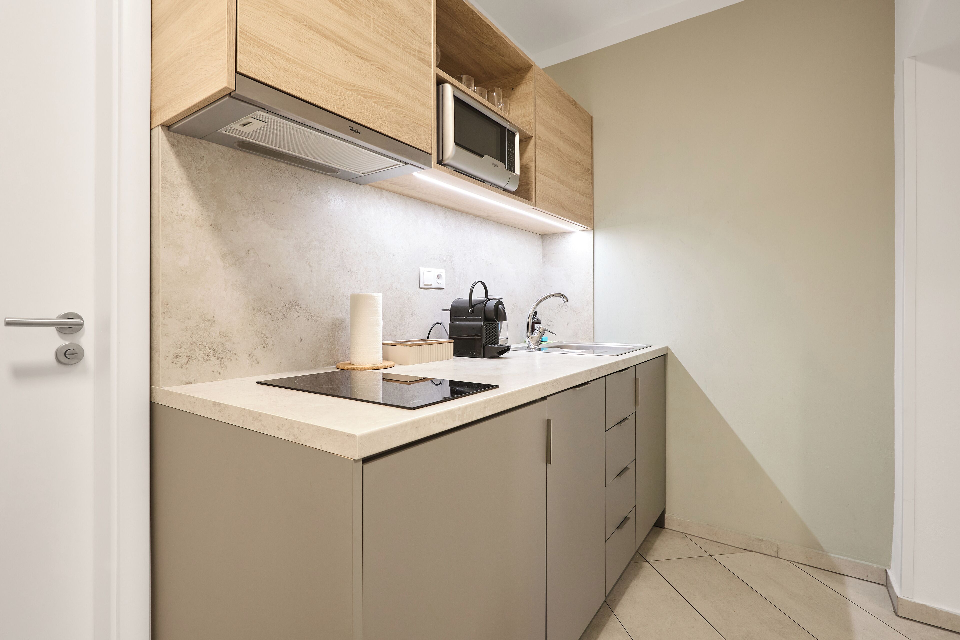 A modern kitchen with a built-in microwave, a kettle, and a coffee maker on the countertop.