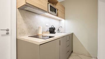 A modern kitchen with a built-in microwave, a kettle, and a coffee maker on the countertop.