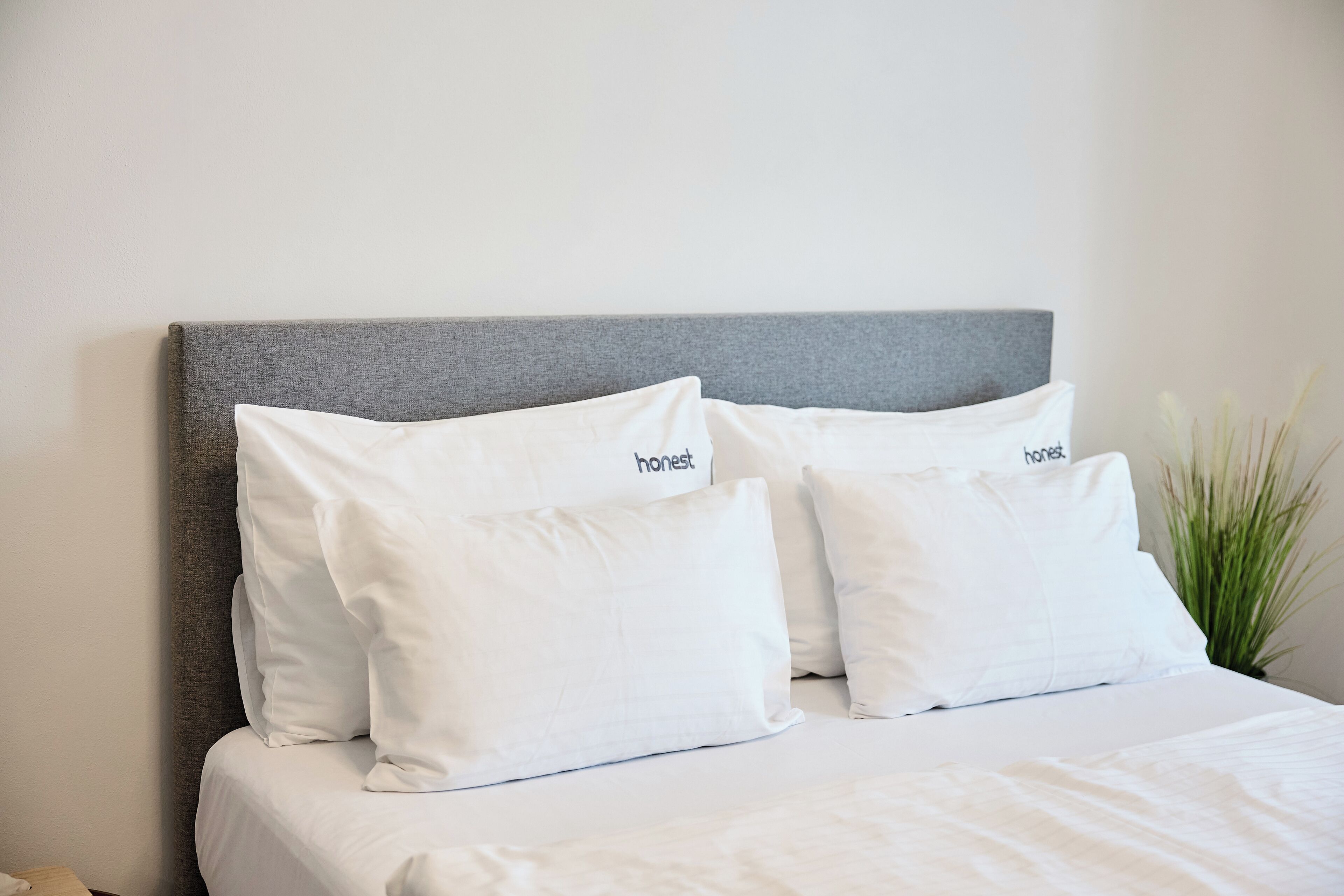 Una cama con cabecera gris y ropa de cama blanca.