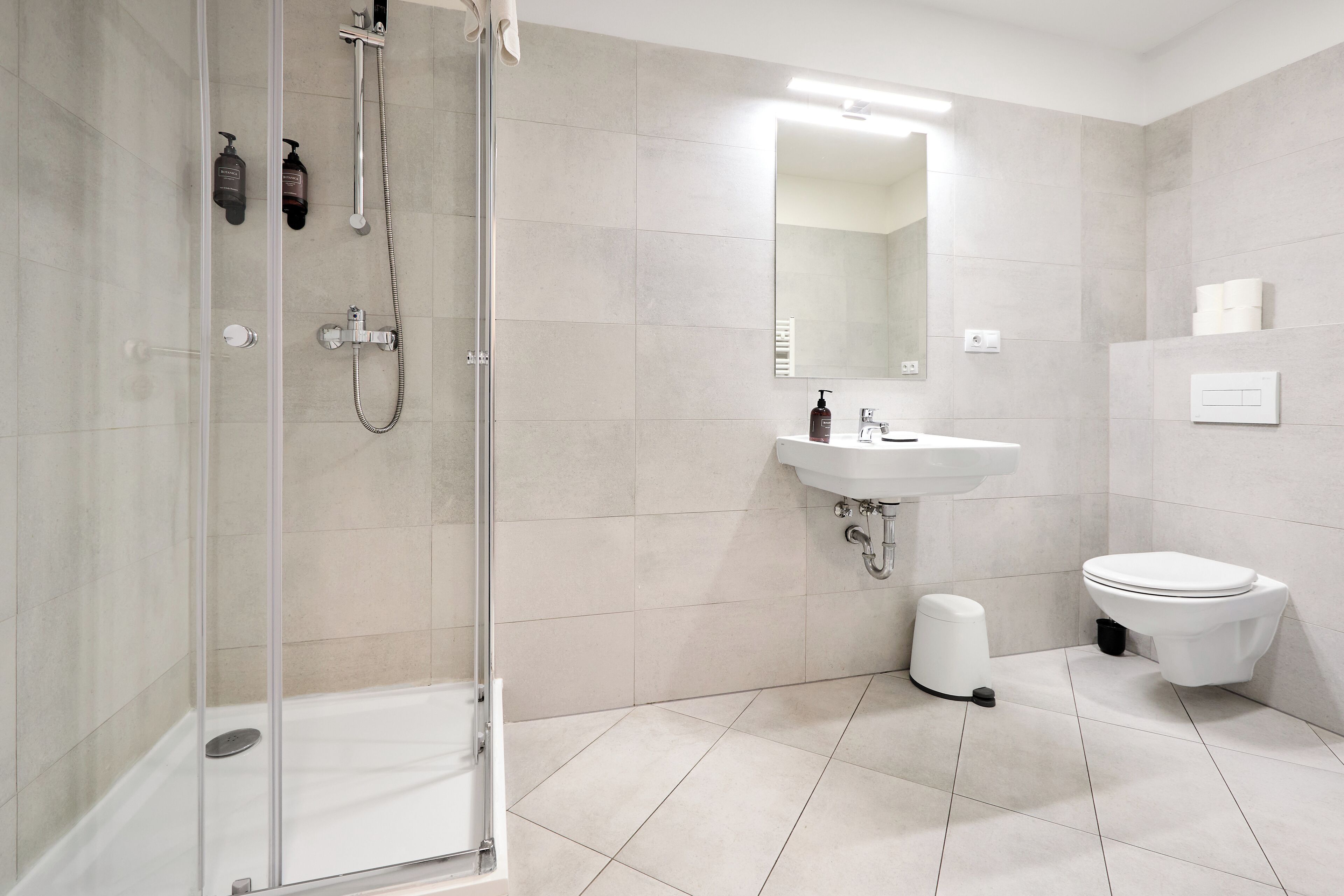 A modern bathroom with a glass shower enclosure, a white sink, and a toilet.