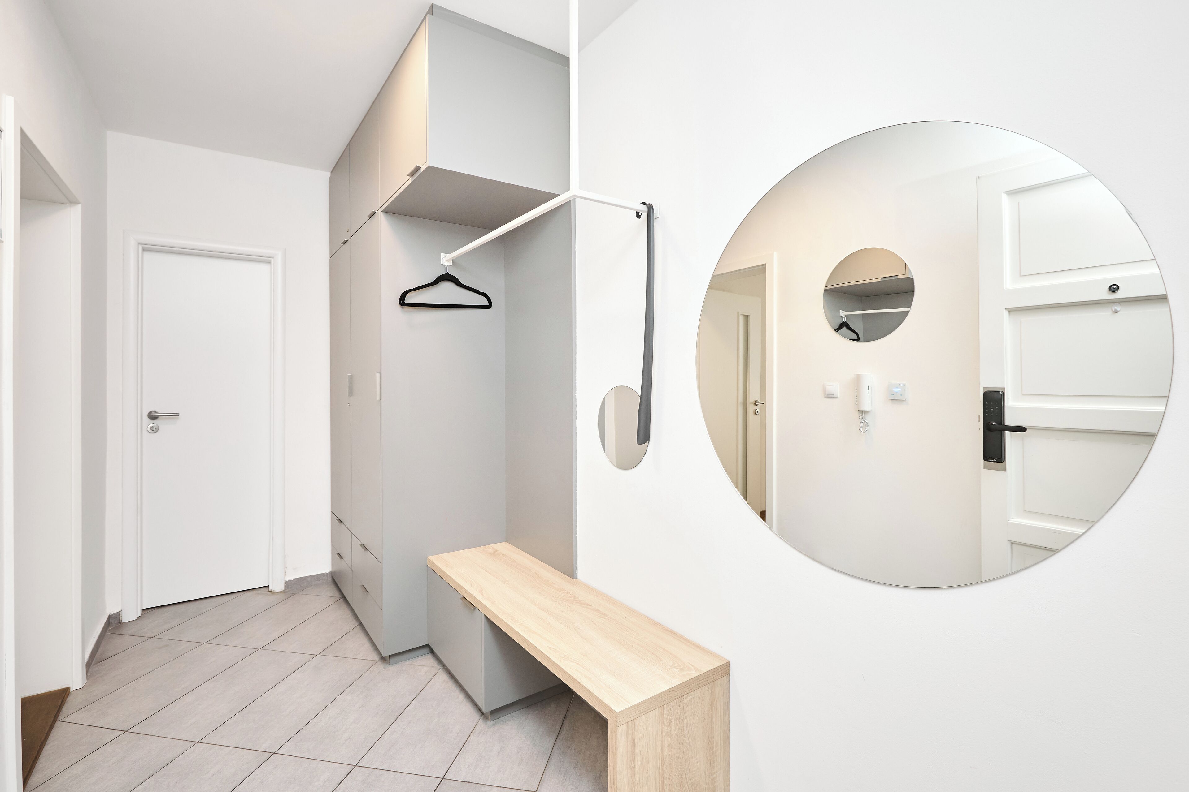 A modern hallway with a bench, a coat rack, and a mirror.