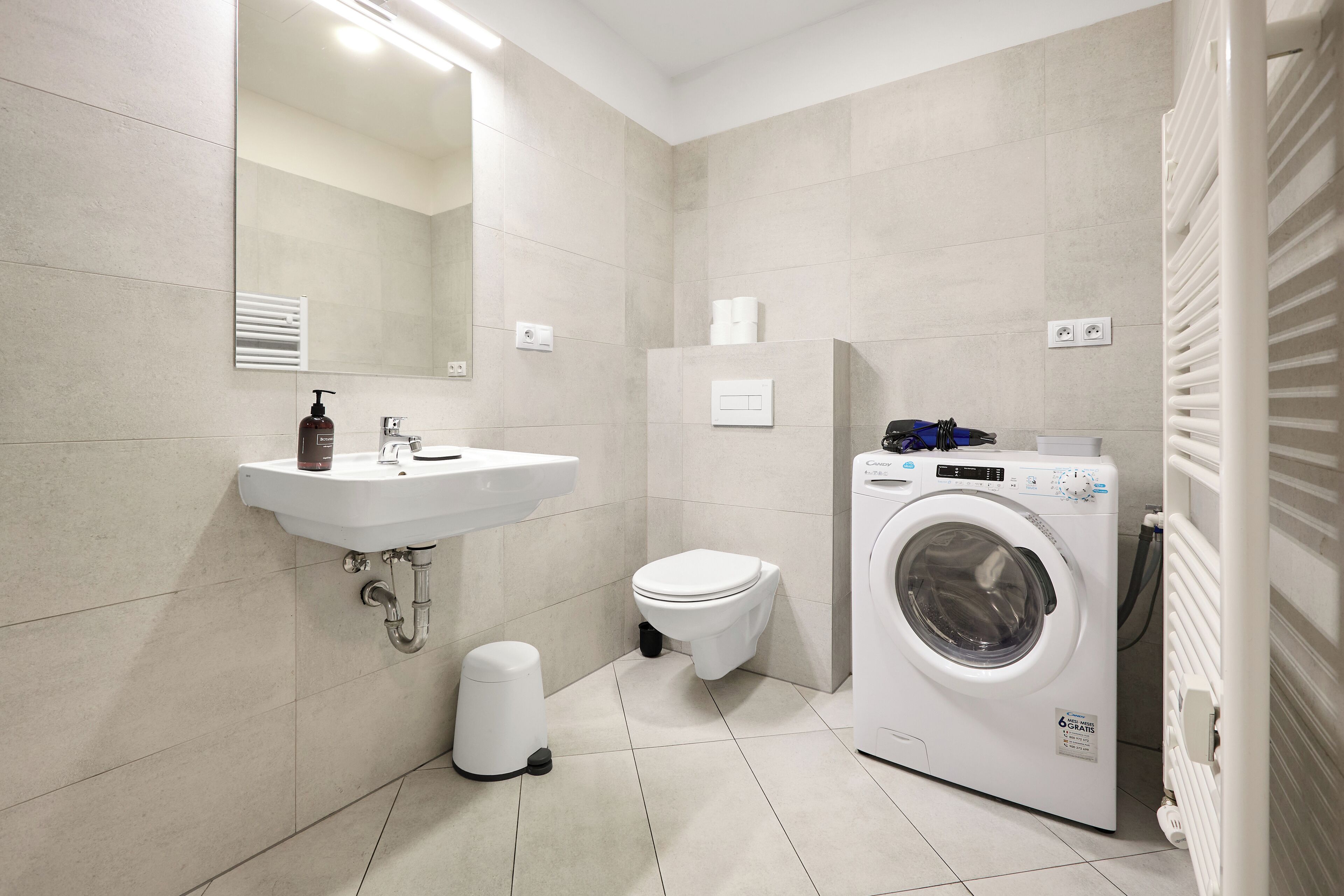 Ein modernes Badezimmer mit Waschbecken, Toilette und Waschmaschine.