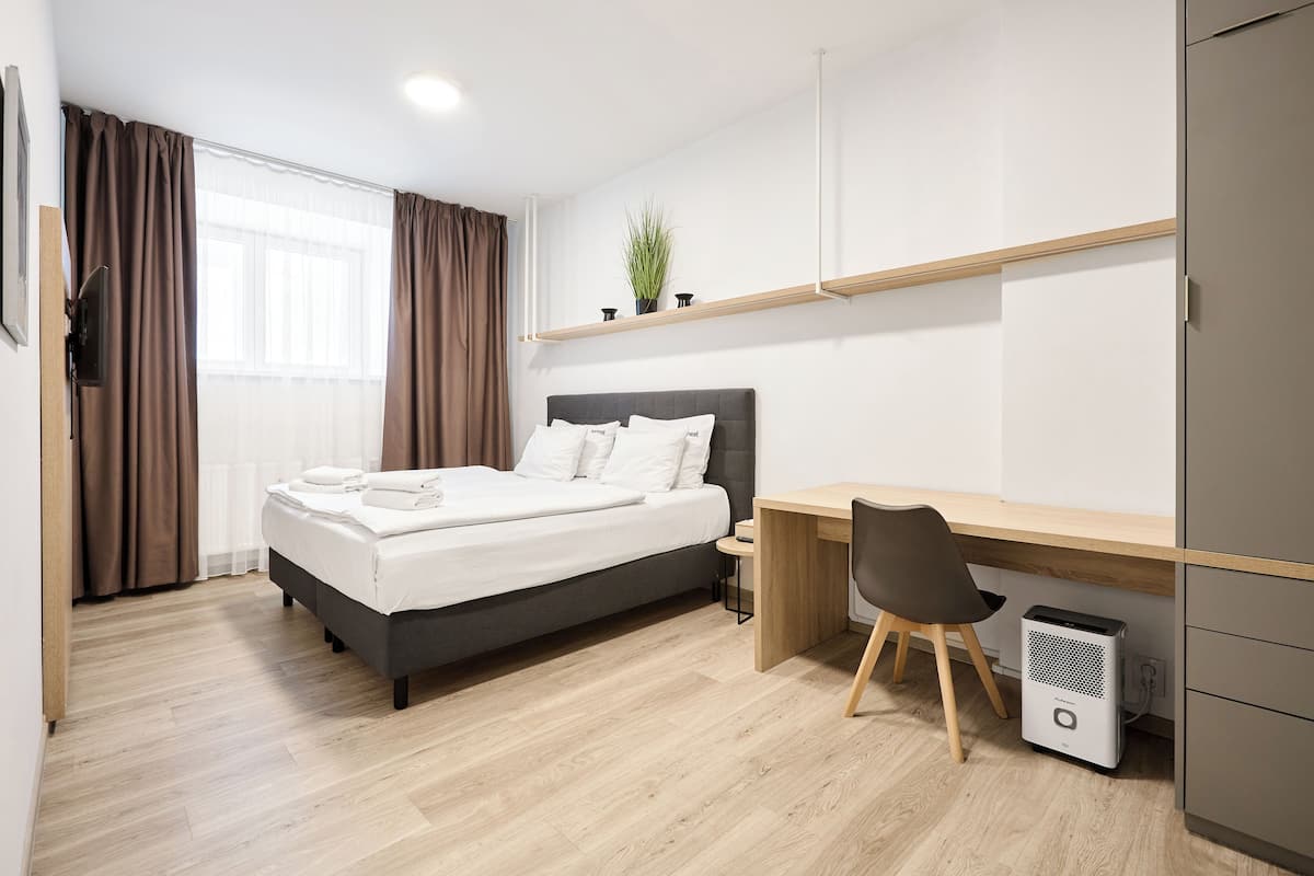 Un dormitorio moderno con cama, escritorio, silla y un pequeño purificador de aire.