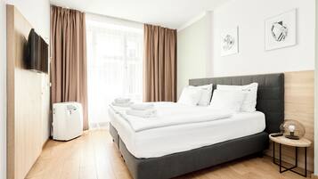 A hotel room with a bed, a TV, a heater, and a small table with a lamp.