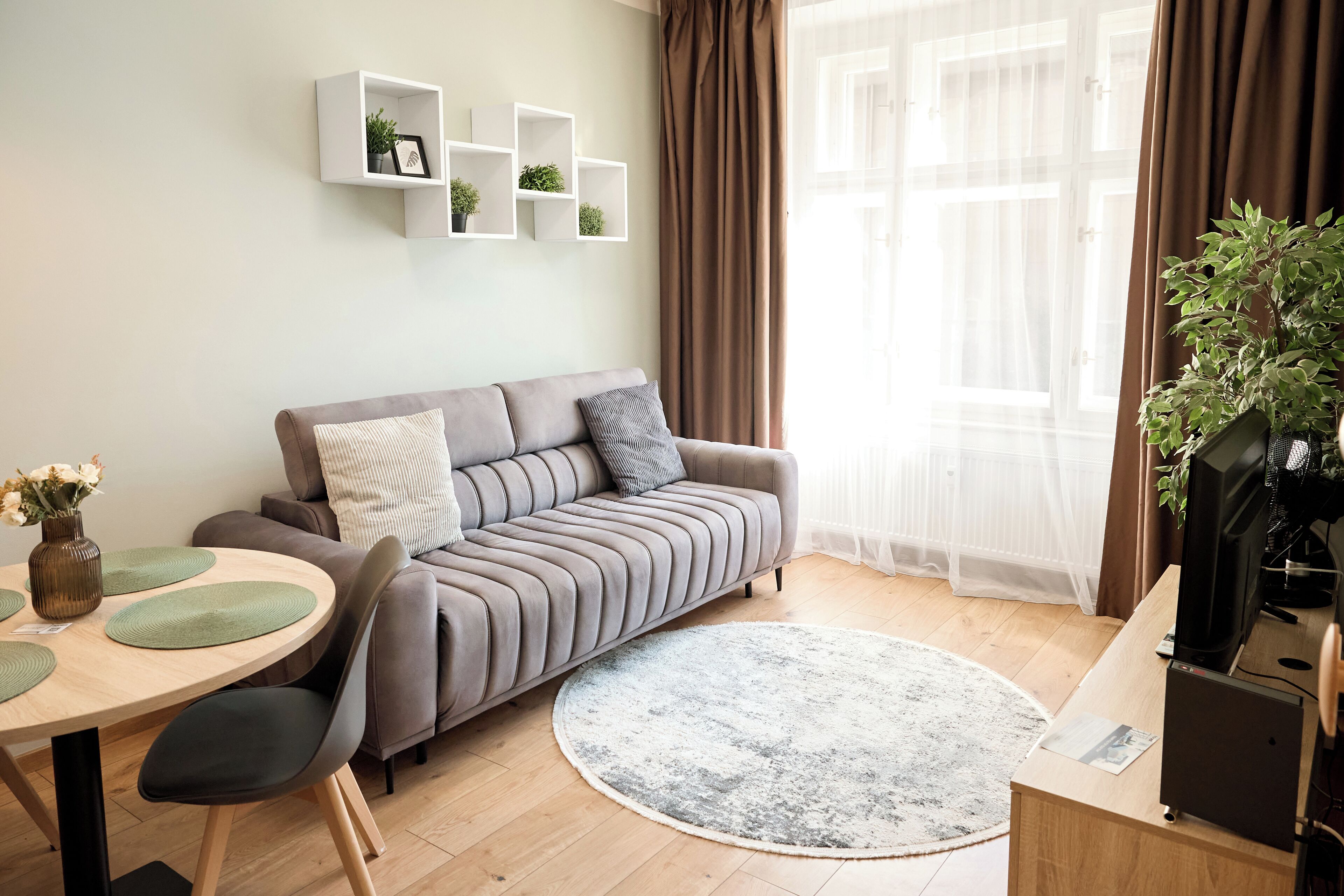 Un salon moderne avec un canapé gris, une table basse ronde et un meuble pour la télévision.