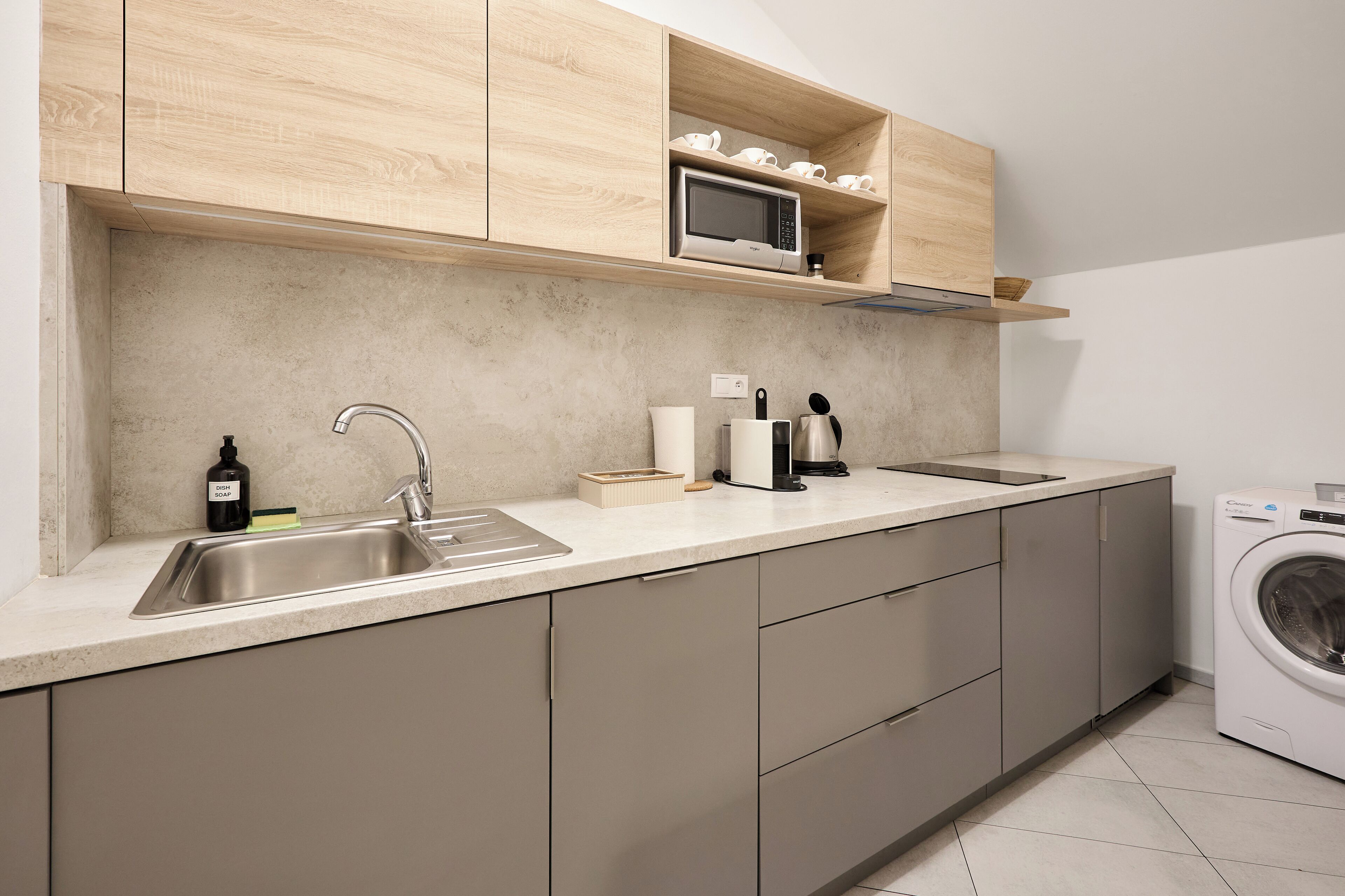 Una cocina moderna con un lavamanos de acero inoxidable, un microondas y una lavadora integrada.