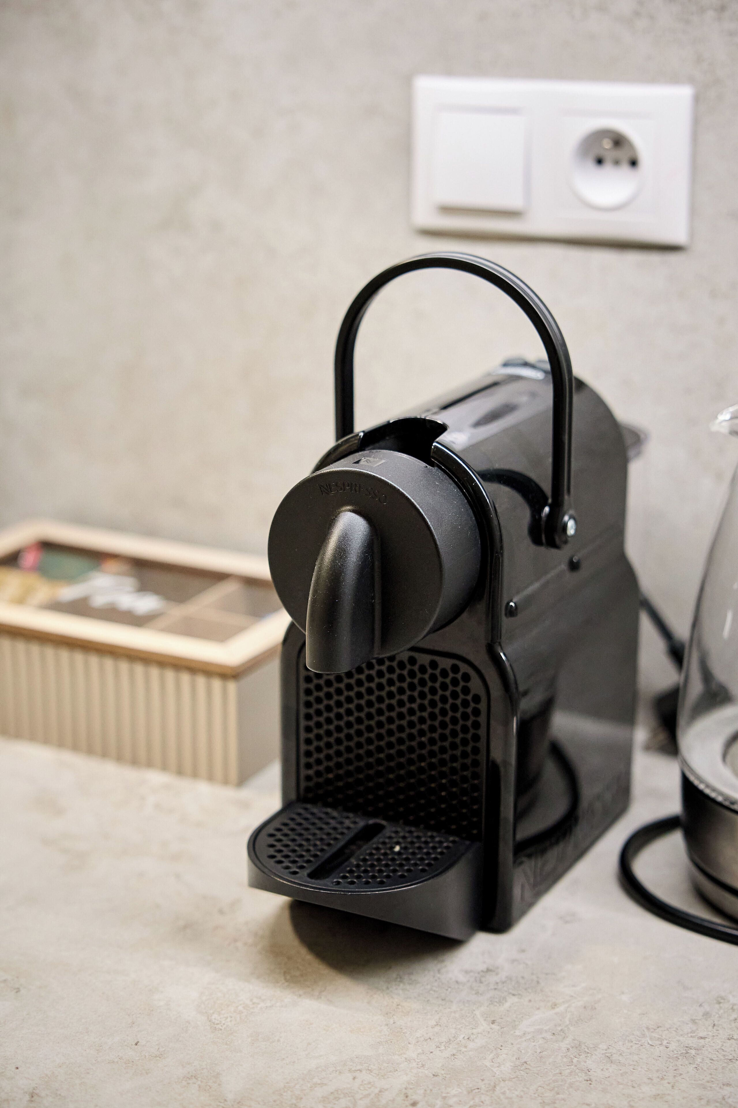 A coffee machine on a countertop with a power outlet in the background.