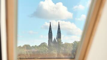 En vy genom ett takfönster i en kyrka med två torn och omgivande grönska.