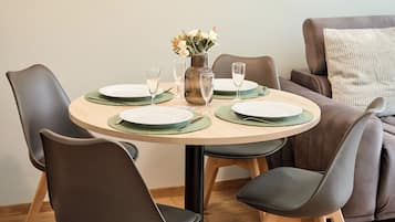 Un coin repas avec une table ronde, quatre chaises, un vase de fleurs et un tableau encadré au mur.