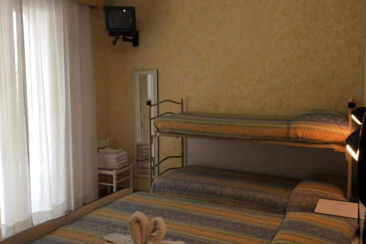 A room with bunk beds, a television, and a window with curtains.
