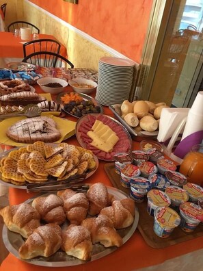 A buffet table with various food items including waffles, pastries, cheese, and condiments. - Hotel Oria Rivabella (Rimini)