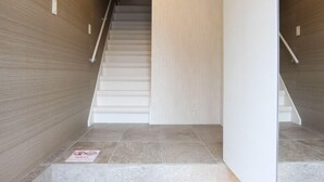 A modern interior with a staircase, tiled flooring, and wooden walls. - The Neighbors (Osaka)
