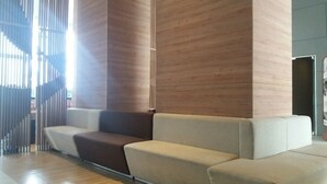 Een moderne wachtruimte met een bank en een houten pilaar.