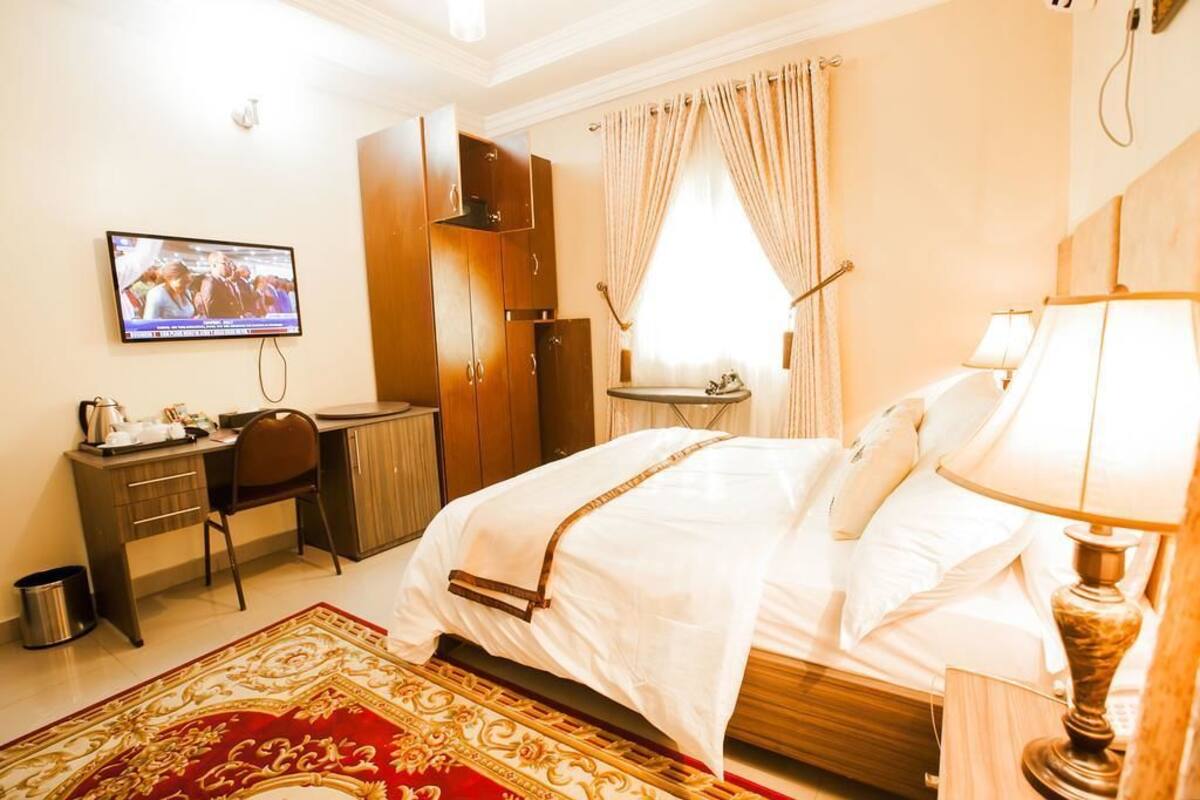 Une chambre d’hôtel avec un lit, un bureau, une télévision et une fenêtre avec des rideaux.