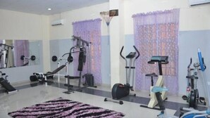 A gym with exercise equipment including a treadmill, stationary bike, and weight machines. - Kanem Suites (Abuja)