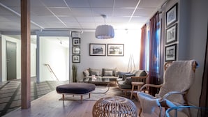 A modern living room with a sofa, chairs, a coffee table, and a unique spherical lamp. - Hotel Akerlund (Jokkmokk)