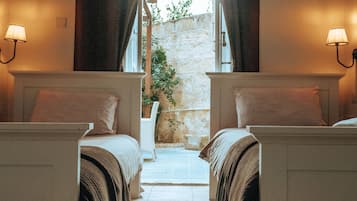 Habitación de hotel con dos camas, cada una con cabecera, lámpara de noche y ventana.