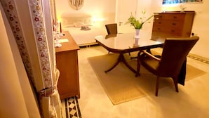 Habitación de hotel con cama, escritorio, silla, mesa, lámpara, un cuadro y cómoda.