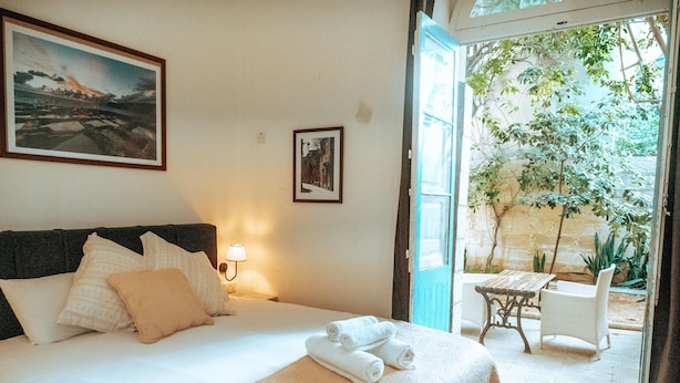 Una habitación de hotel con cama, mesita de noche, lámpara y vistas del patio exterior.