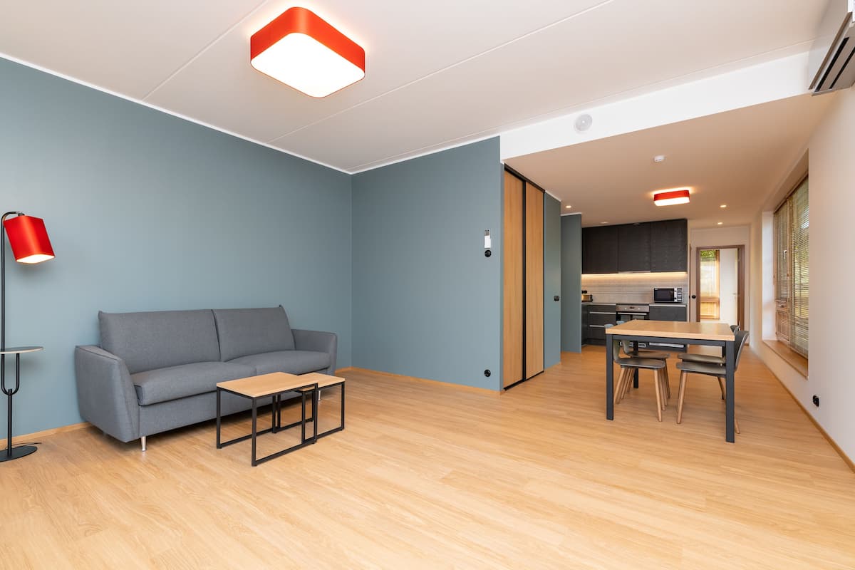 Ein modernes Wohnzimmer mit einem grauen Sofa, einem Holztisch und einer roten Stehlampe.