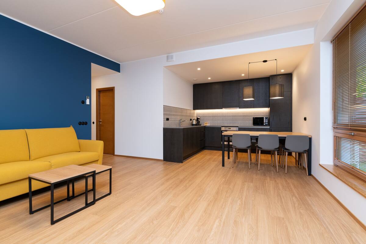 Eine moderne Küche mit dunklen Schränken, einem Holztisch und vier Stühlen.