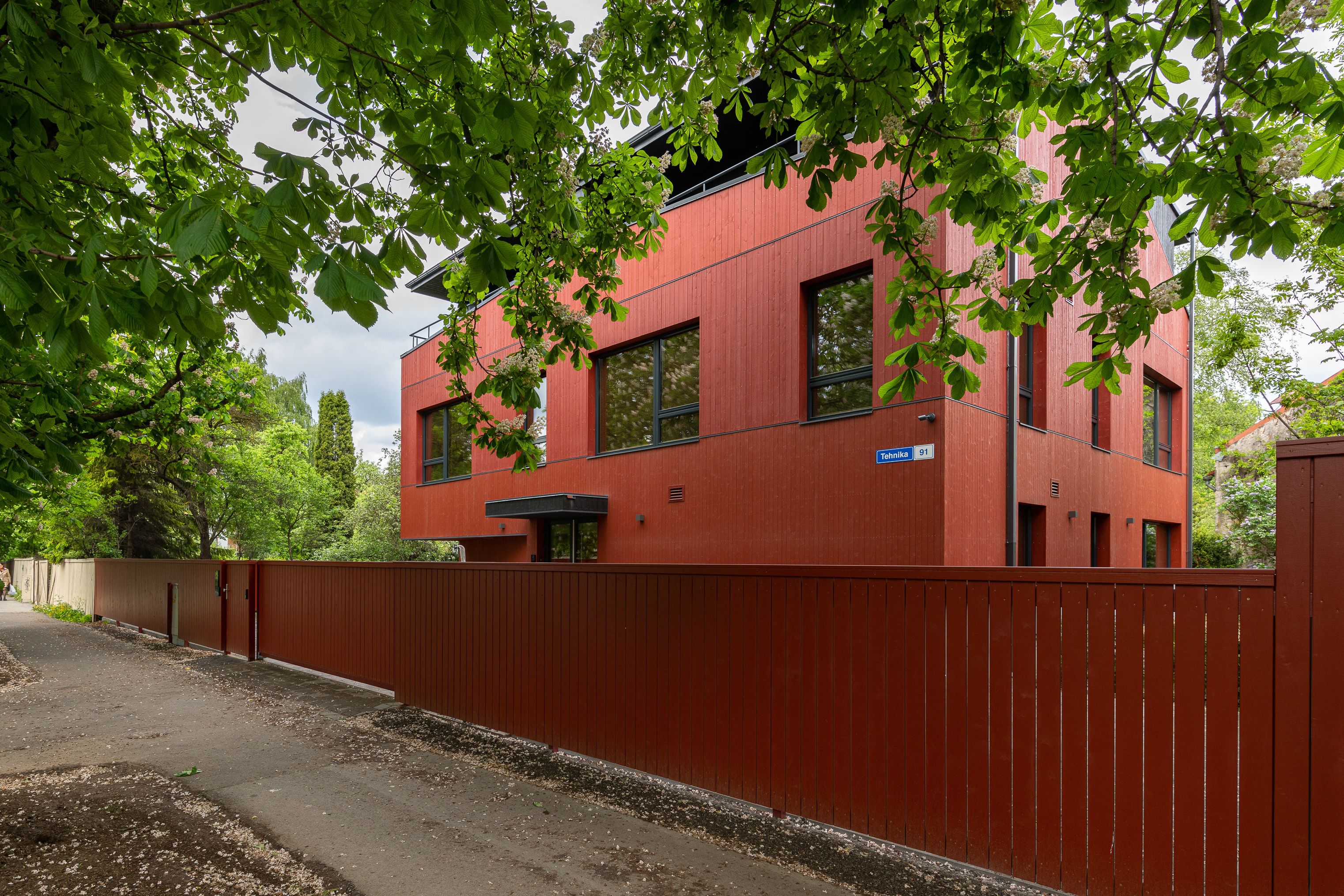 A red building with a blue sign, surrounded by a fence and trees.