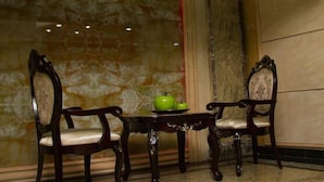 A room with two wooden chairs, a small table, and a green teapot. - Landmark Hotel (Port Harcourt)