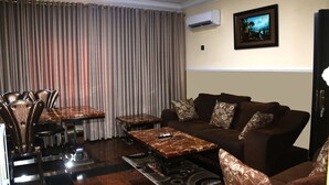 A living room with a brown sofa, a dining table with chairs, and a coffee table. - Landmark Hotel (Port Harcourt)