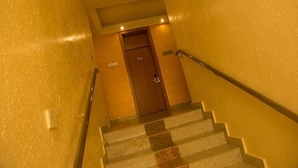 A staircase with a wooden door at the top, a handrail on the right, and a sign on the wall. - Landmark Hotel (Port Harcourt)