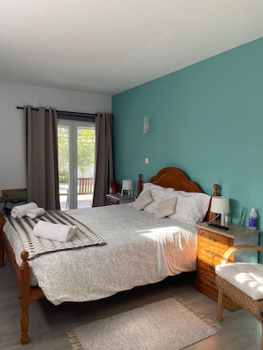 Un dormitorio con cama, mesitas de noche, cortinas en la ventana y vistas al exterior.