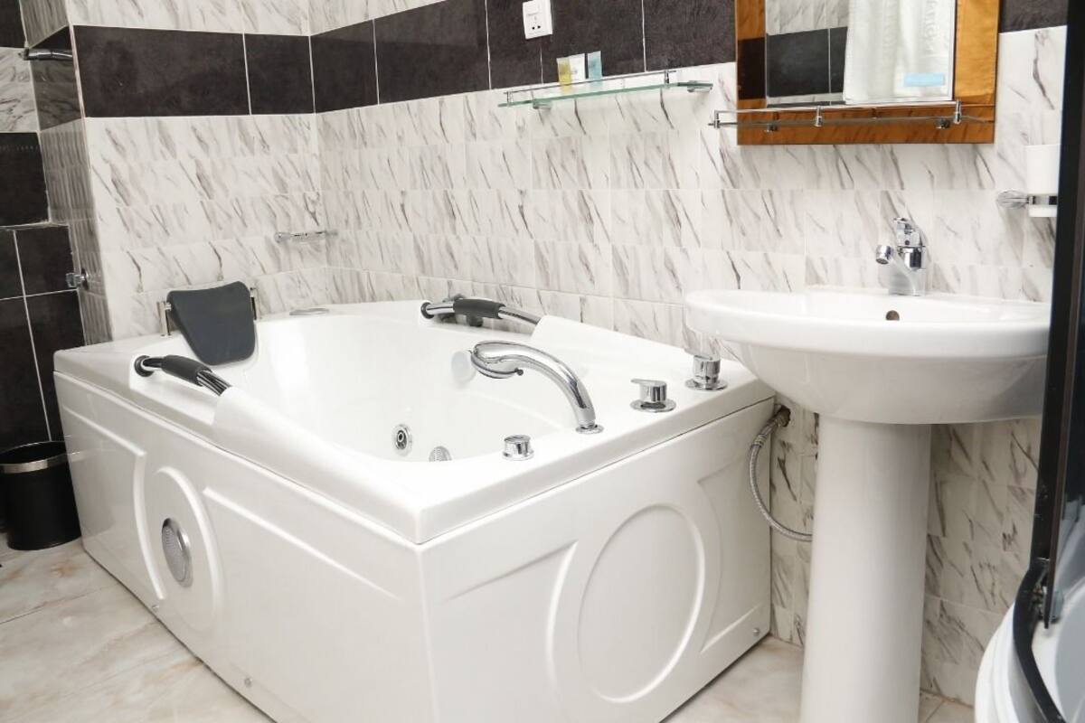 Un bagno con una vasca da bagno bianca, un lavandino e uno specchio sopra il lavandino.