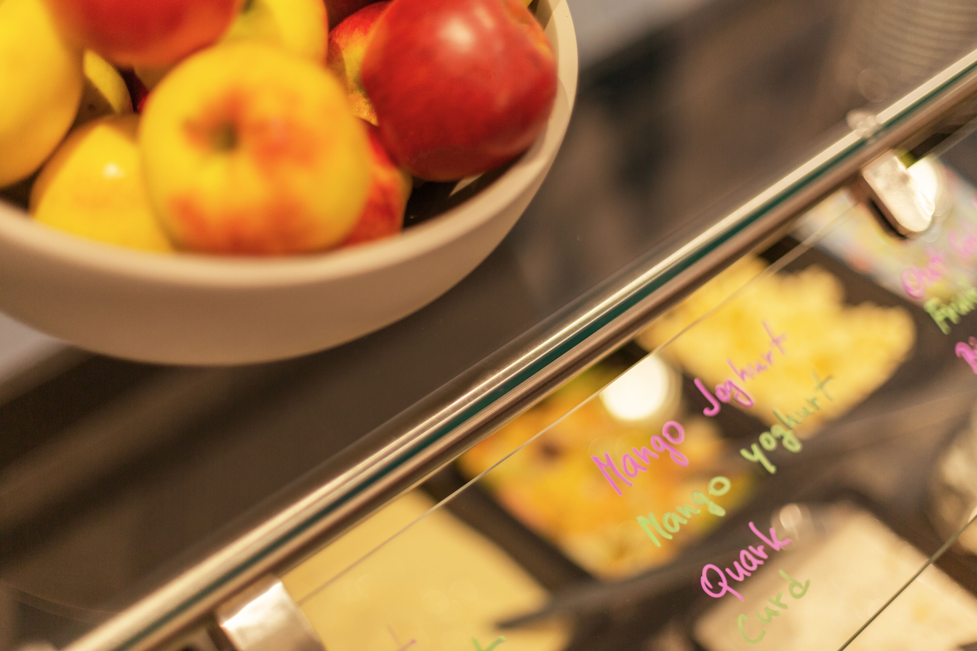 A bowl of fruit with a handwritten note listing mango yogurt and quark.