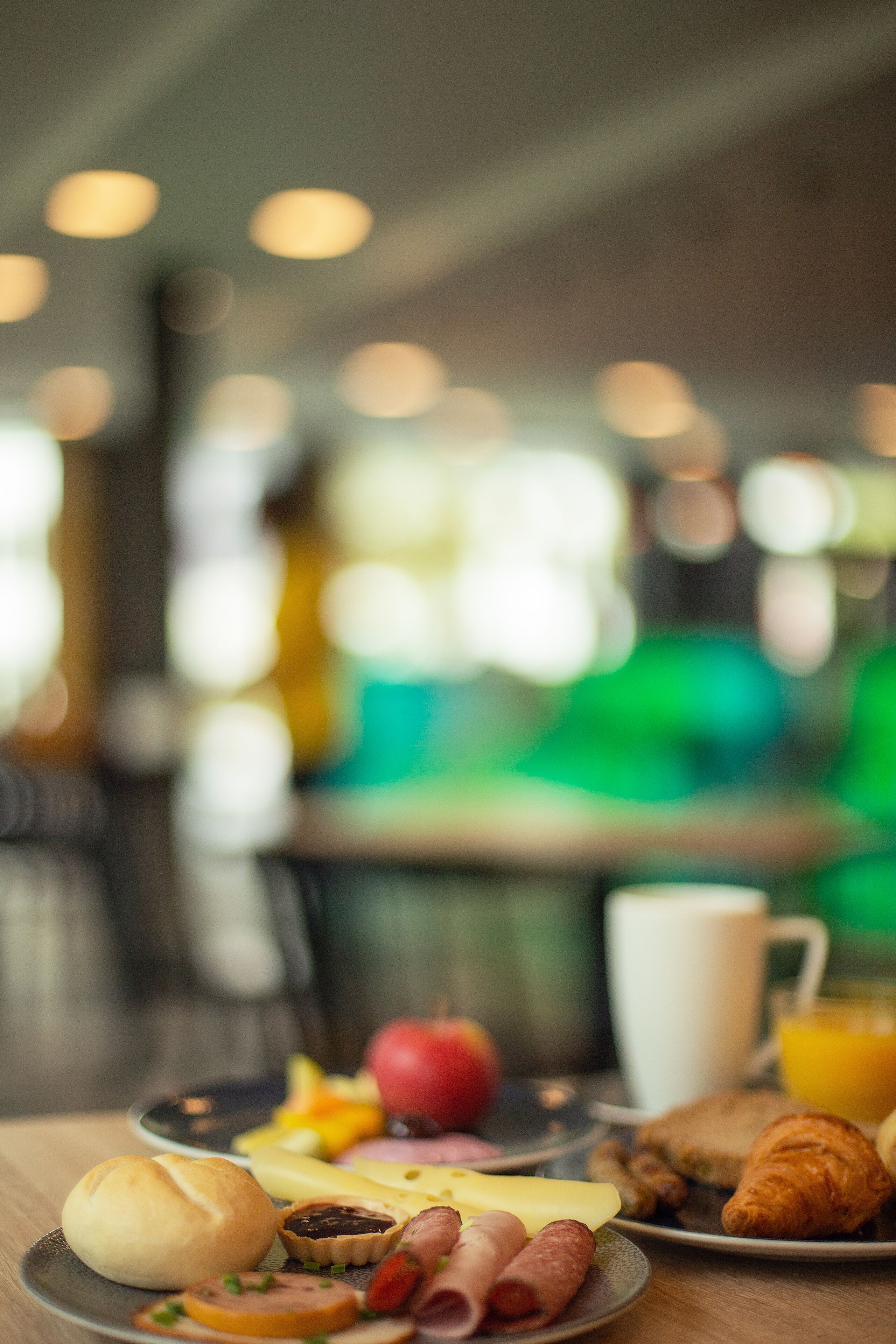 A breakfast setting with a plate of food, a croissant, and a glass of orange juice.