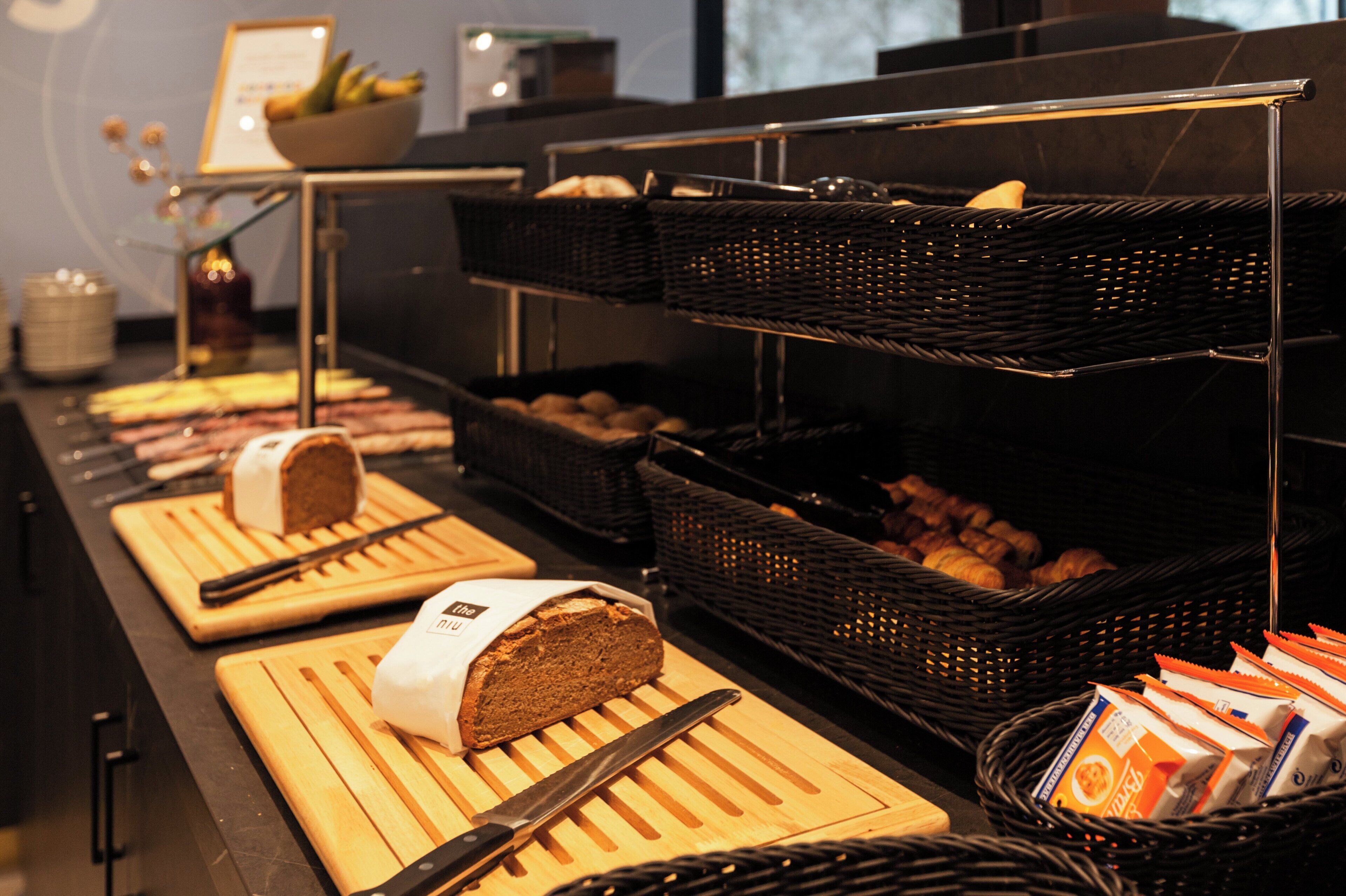 Ein Buffet mit verschiedenen Brotsorten und Gebäcken, präsentiert auf Holzbrettern und Korbflechtern.
