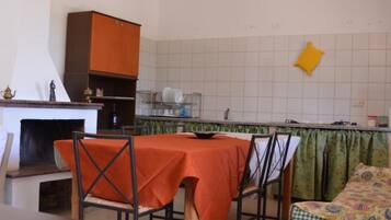 A compact kitchen with a dining table, chairs, and a sofa.