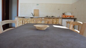 A kitchen with a dining table, chairs, a cutting board, and a basket.
