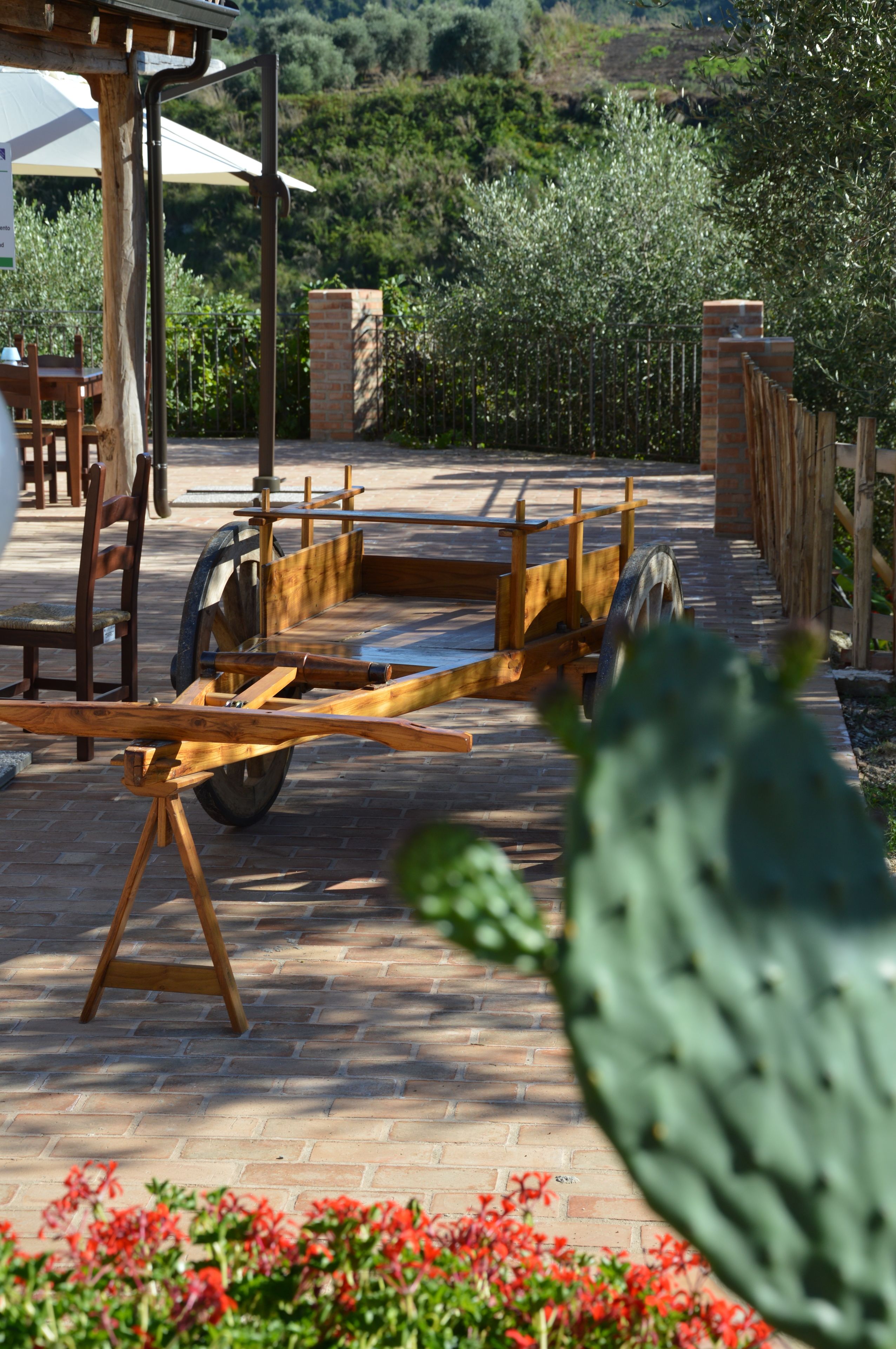A patio area with a wooden table and chairs, a brick wall, and a cactus plant.