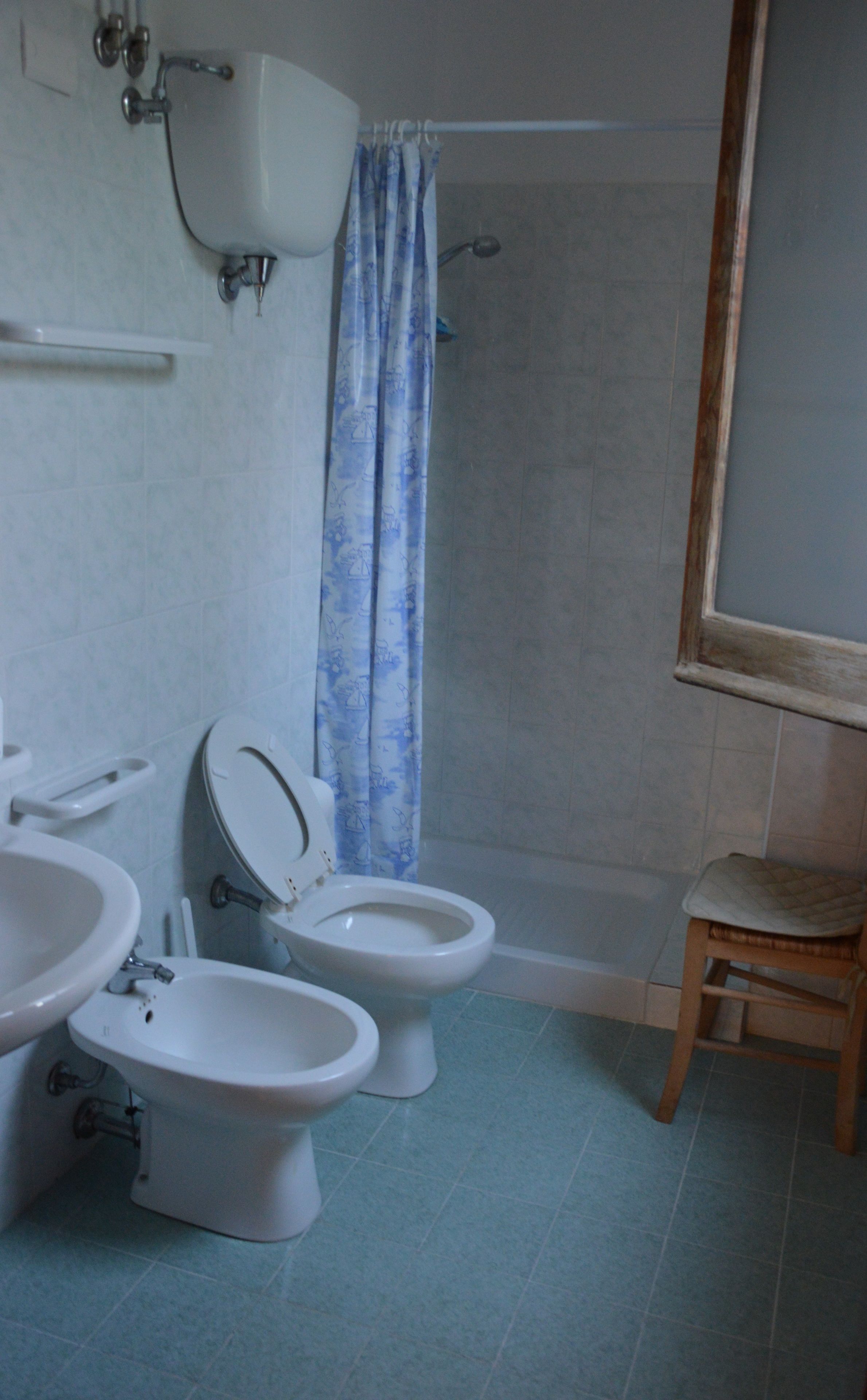 A bathroom with two toilets, a sink, and a shower.