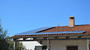 A building with a tiled roof, a chimney, and solar panels.