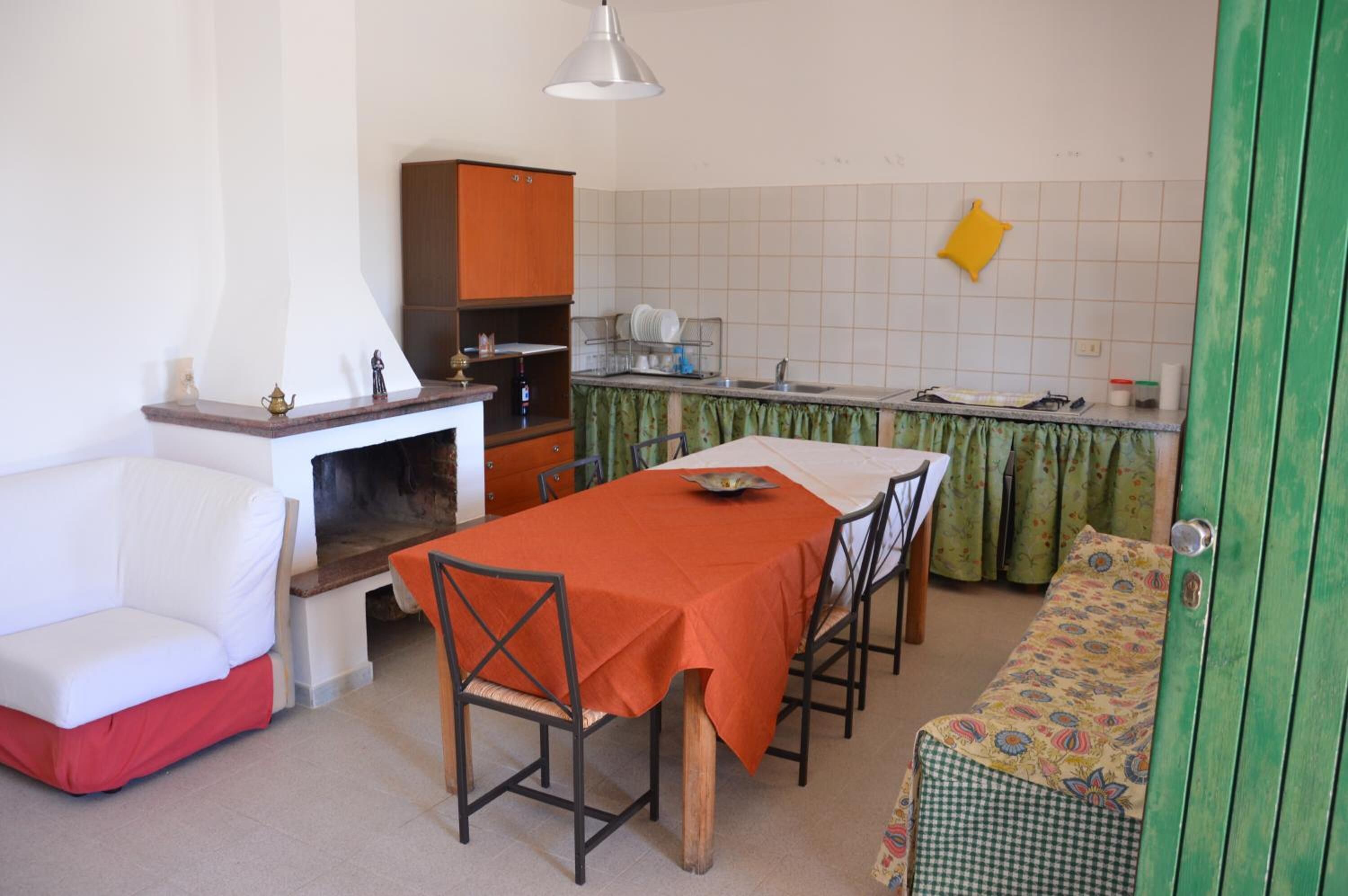 A compact kitchen with a dining table, chairs, a sofa, and a bench.