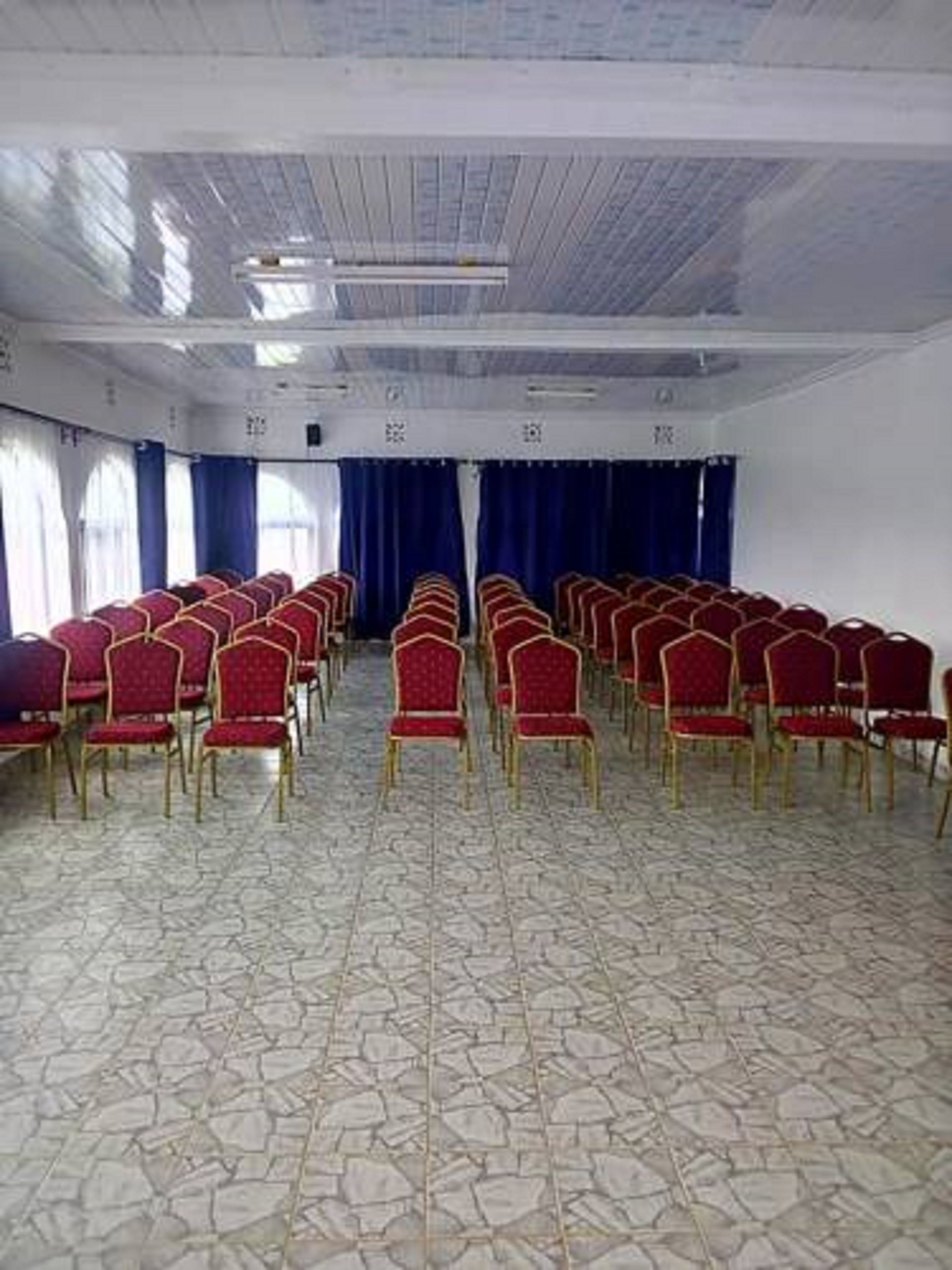 A conference room with rows of red chairs and a patterned floor.