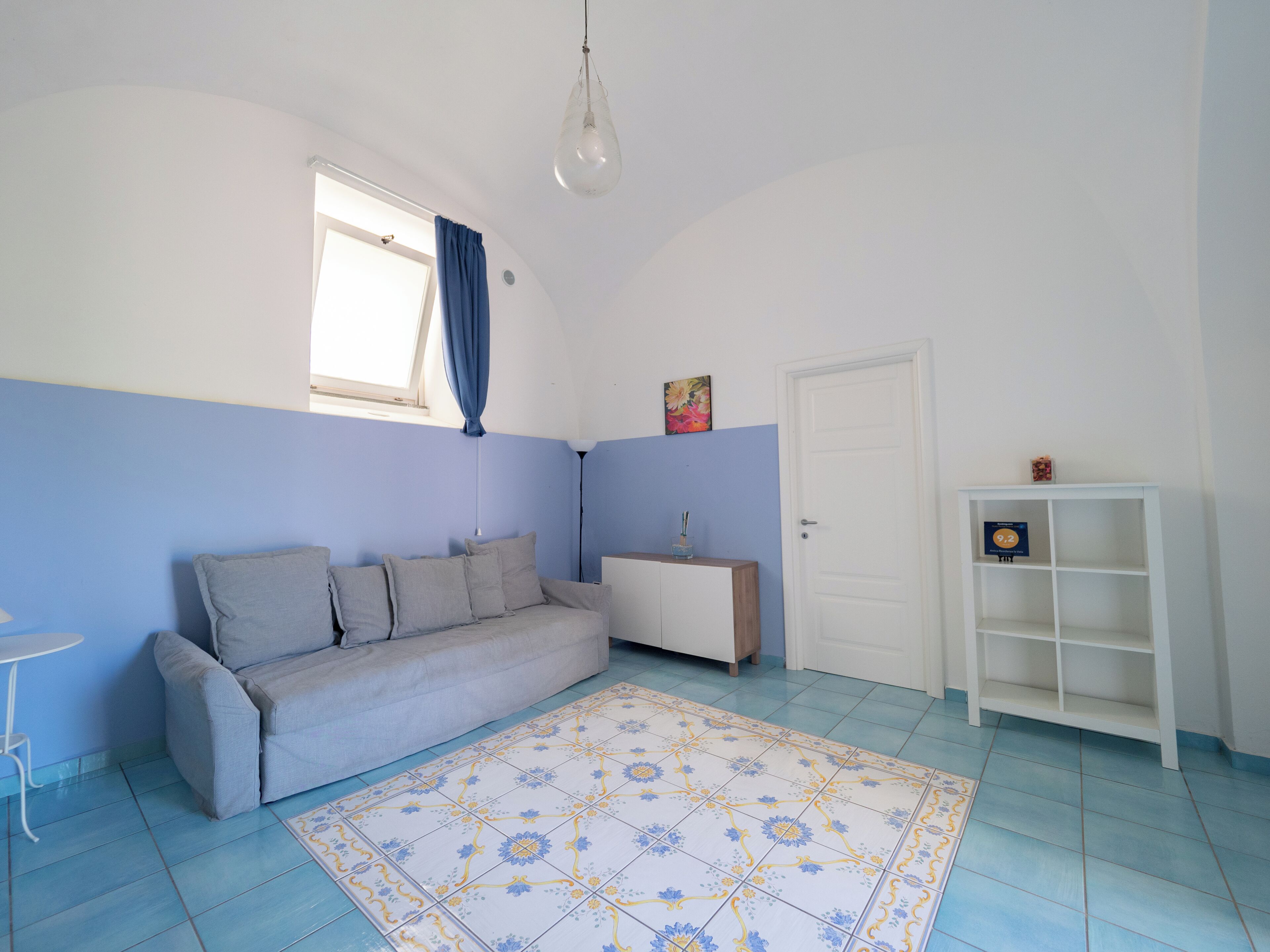 A room with a sofa, a small table, a cabinet, a door, and a patterned rug.