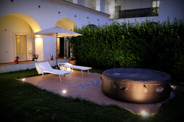 Un patio con dos sillones de descanso, una sombrilla grande y un jacuzzi.