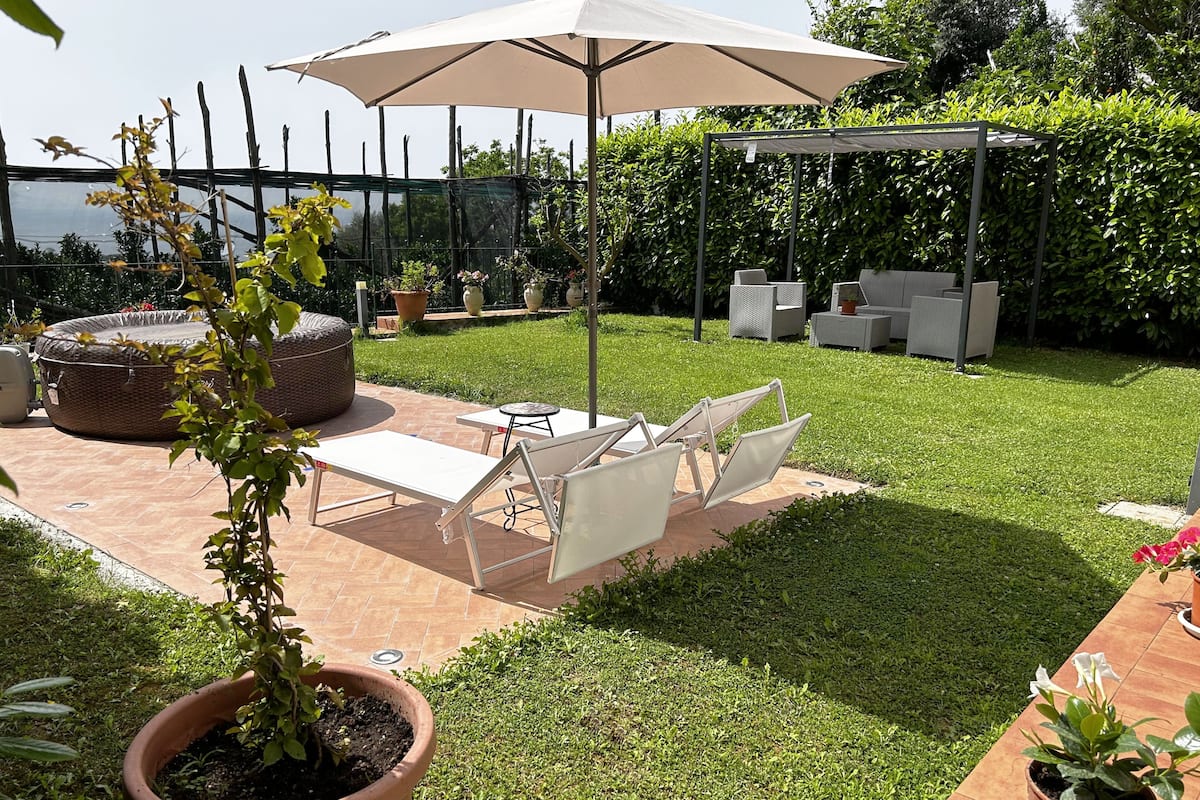 Uma área de pátio com pérgola, móveis de exterior e plantas em vasos.