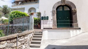 A building with a stone wall, a green door, and a staircase leading to a white entrance. - Antica Residenza la Vela (Meta)