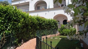 A building with a white facade, multiple arches, and a green hedge in the foreground. - Antica Residenza la Vela (Meta)